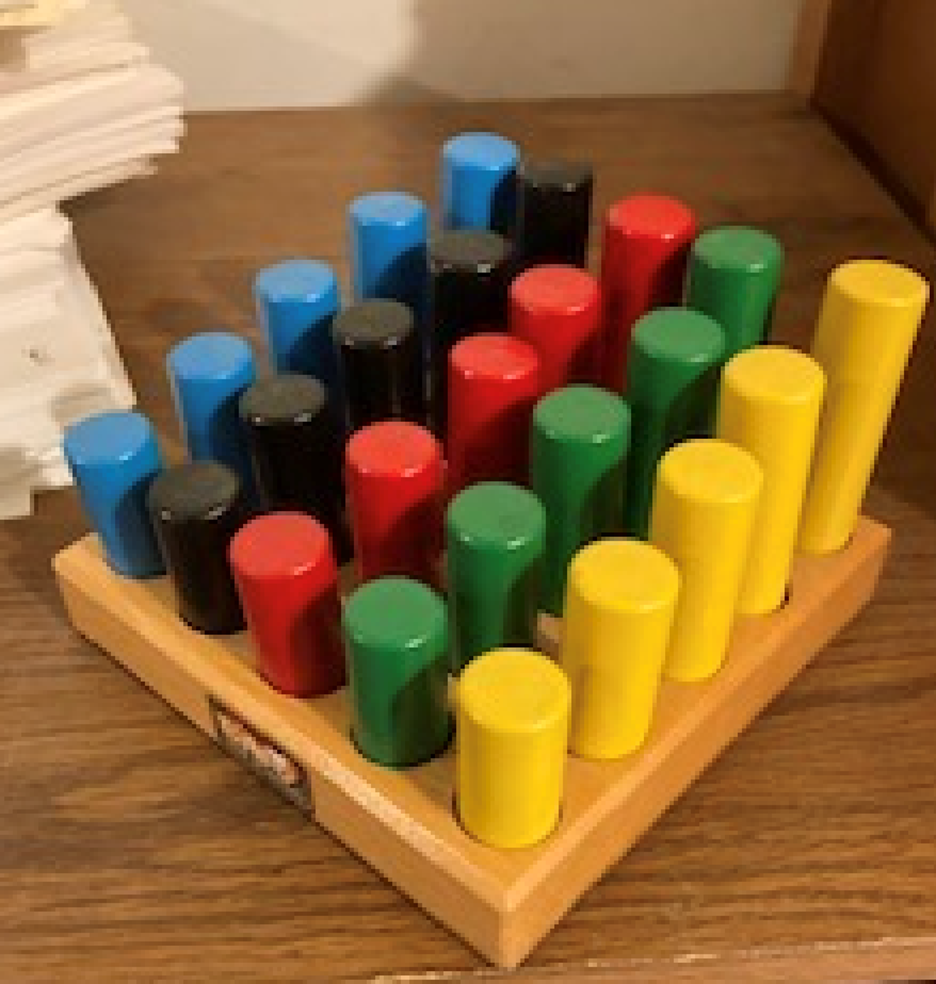 Photo showing blue, black, red, green, and yellow wooden pegs lined up in a wooded base organized by height.